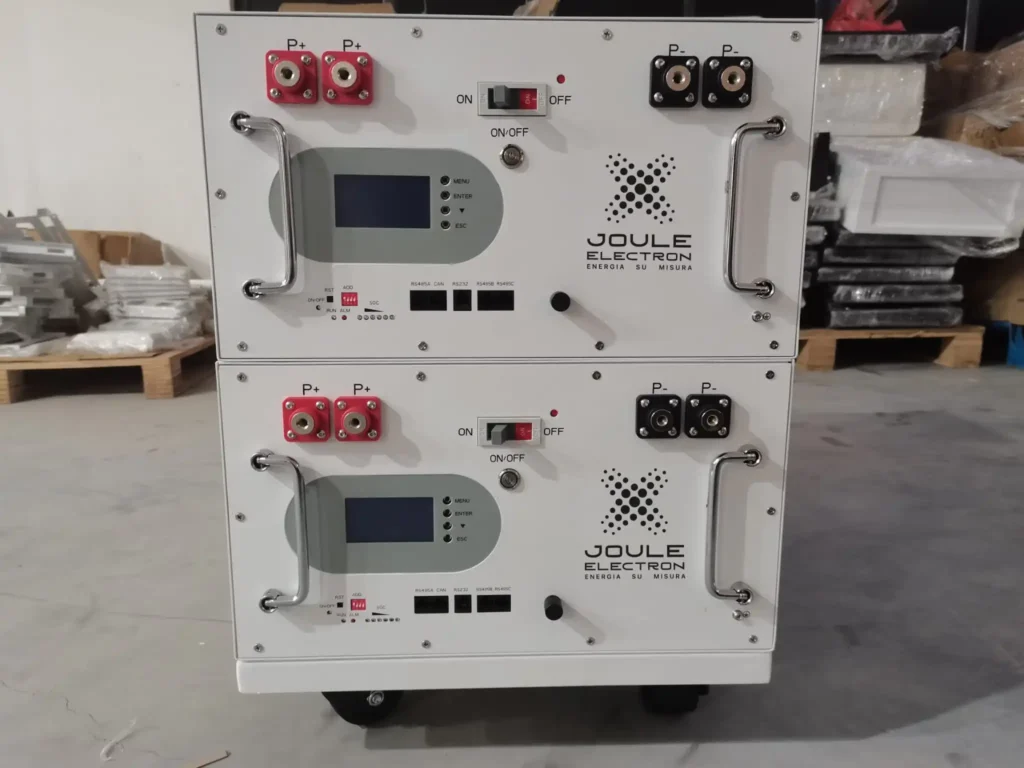 Due moduli batteria impilati di colore bianco con maniglie, un display digitale e il logo "JOULE ELECTRON", montati su ruote.